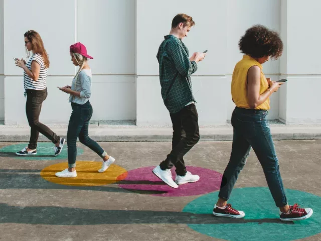 young adults walking around looking at their phones
