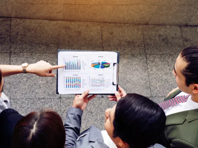 Asian business coworkers reviewing charts ona a tablet