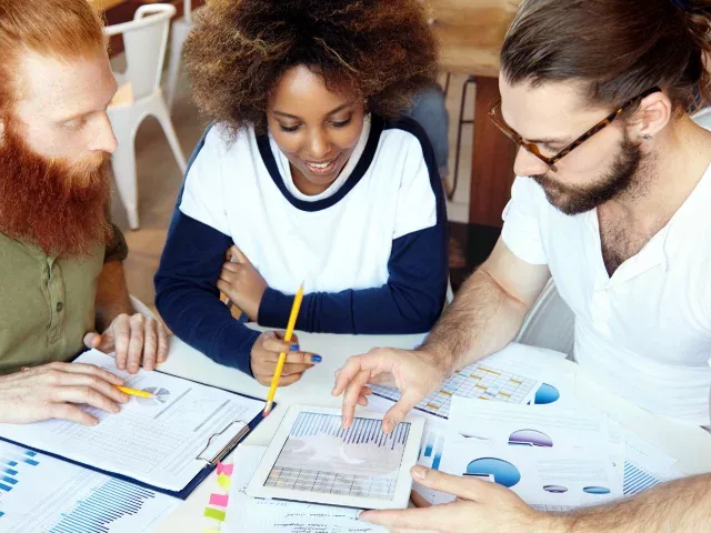 diverse team planning campaign with printouts of charts and graphs
